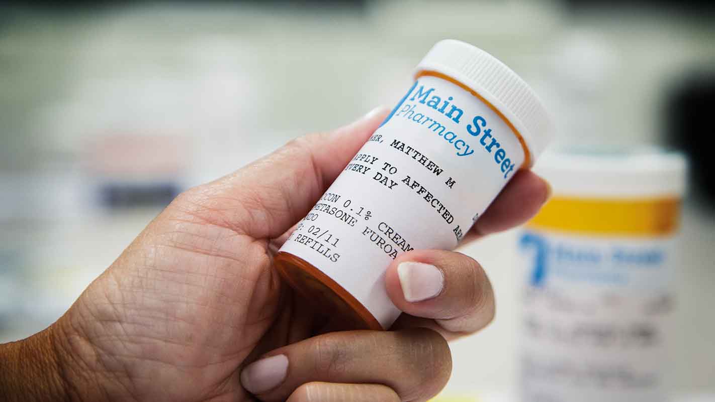 Closeup of a pharmacist holding a prescription pill bottle