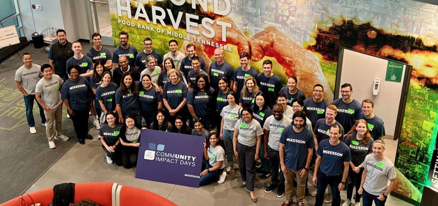 A group of people wearing McKesson shirts pose with a "Community Impact Days" sign at Second Harvest.