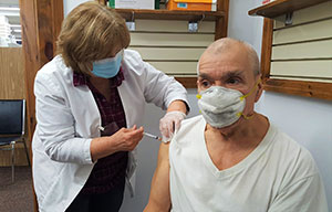 A pharmacist administering a vaccine in a man's arm