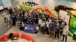 A group of people wearing McKesson shirts pose with a "Community Impact Days" sign at Second Harvest.