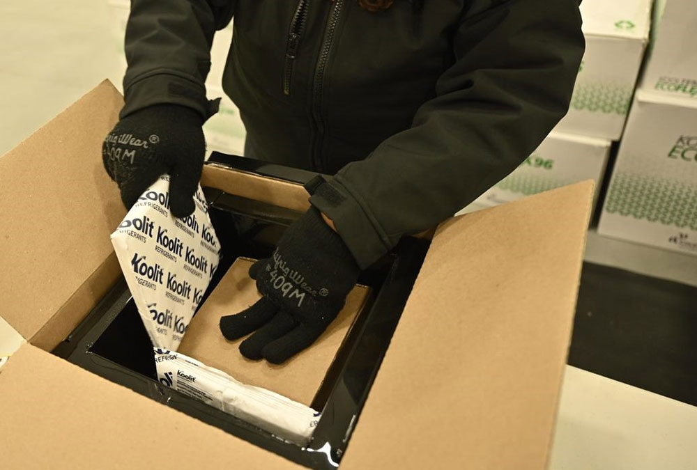 A worker packing a box of Moderna vaccines with cold packs