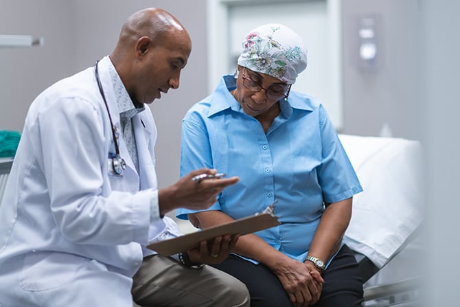 A doctor holding a clipboard talking to a patient