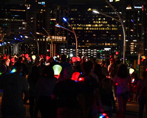 A crowd of people holding candles on a city street at night.