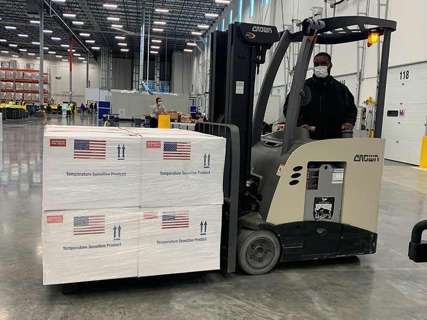 Employee working in warehouse driving forklift