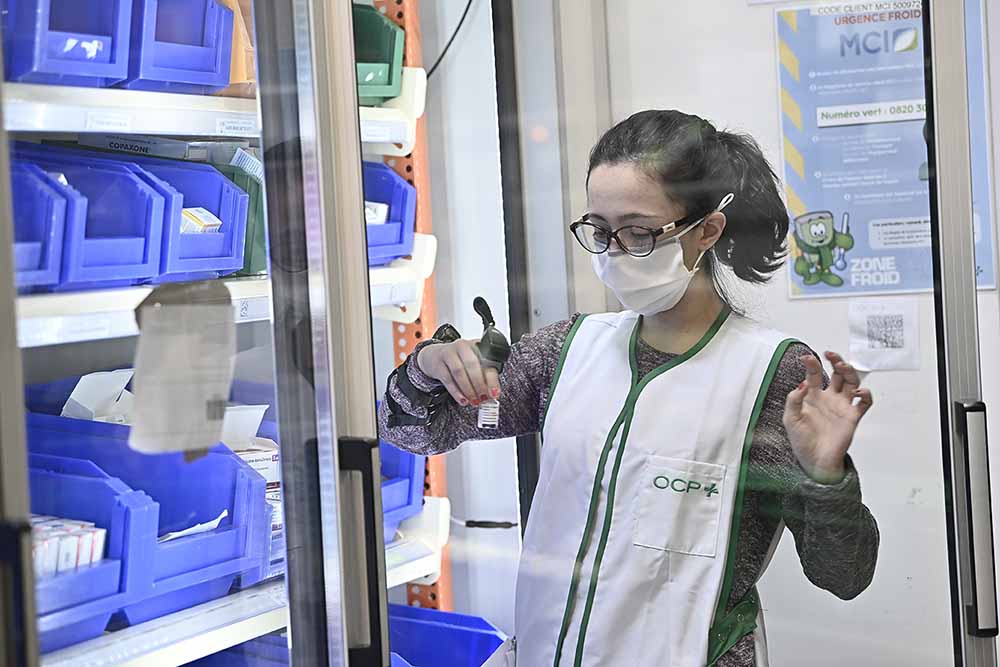 A pharmacy worker holding a COVID-19 vaccine vial