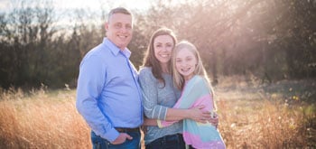 A man, woman and child stand together and embrace