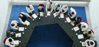 Aerial view of a business meeting with people seated around a U-shaped table.