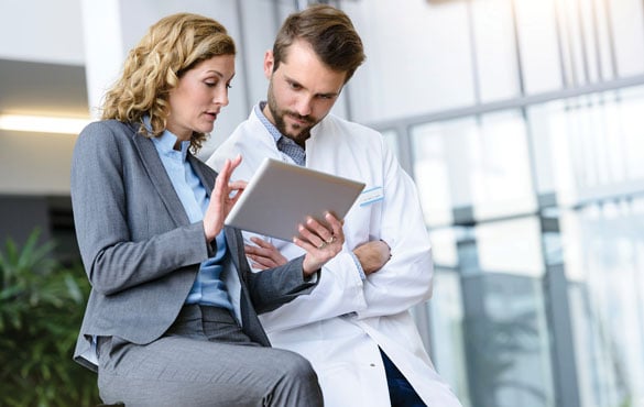 A business person and a doctor chat in a hospital corridor